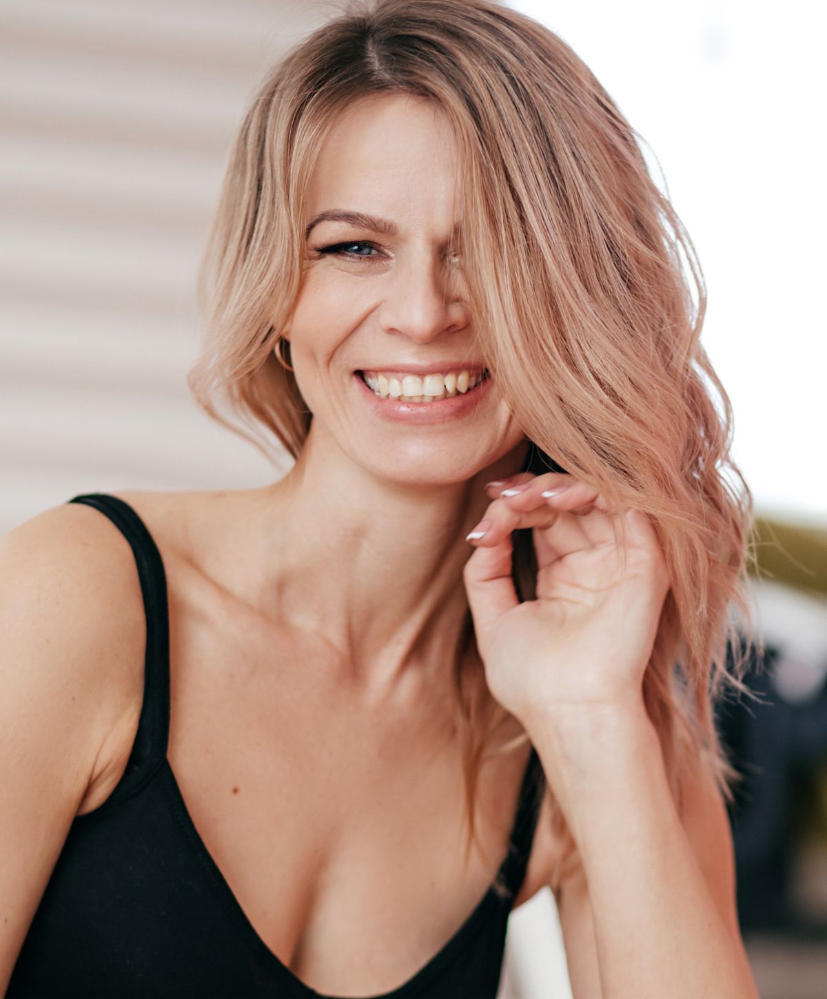 Smiling woman with wavy blonde hair indoors.