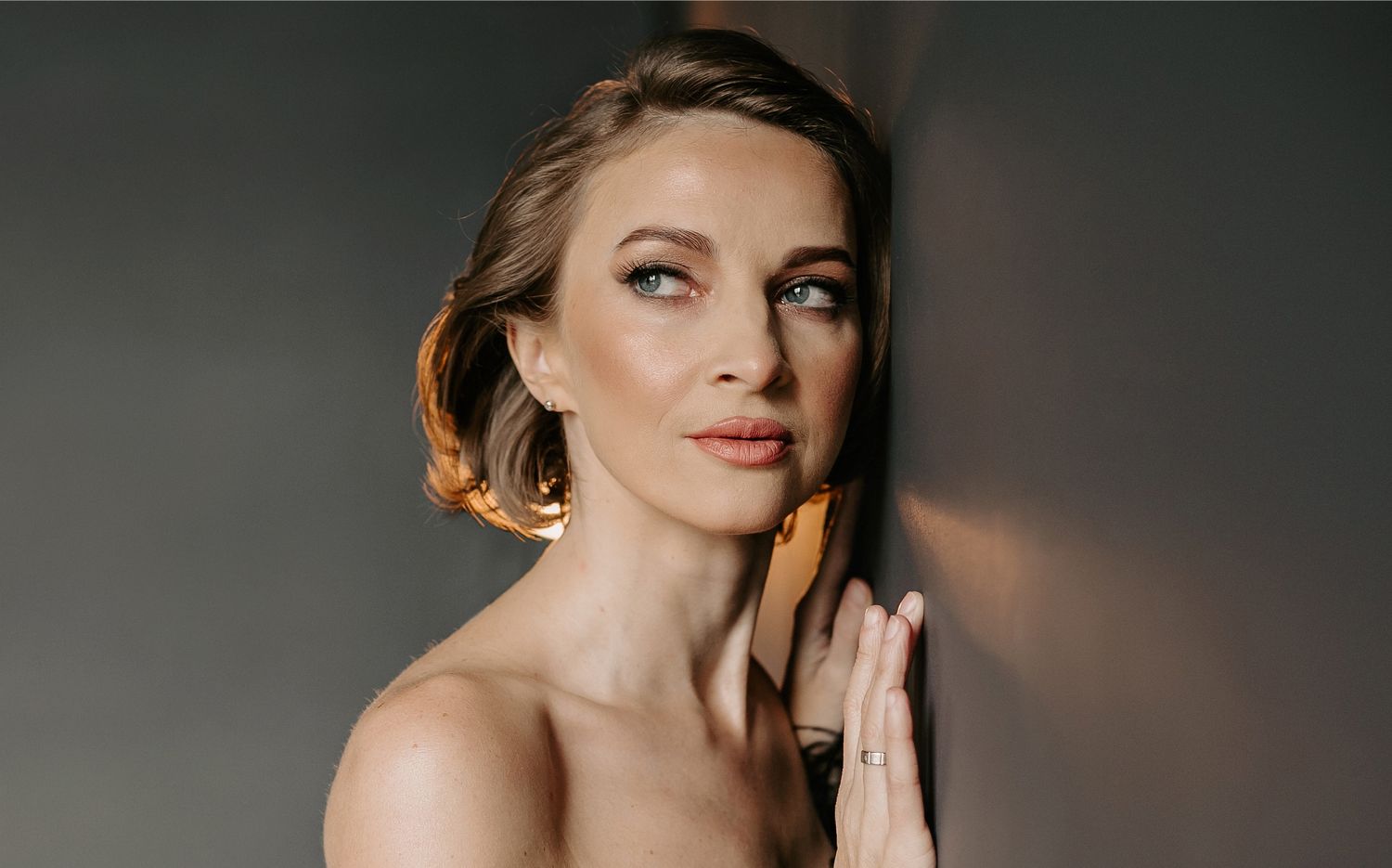 Woman gently touching her face, looking thoughtful.