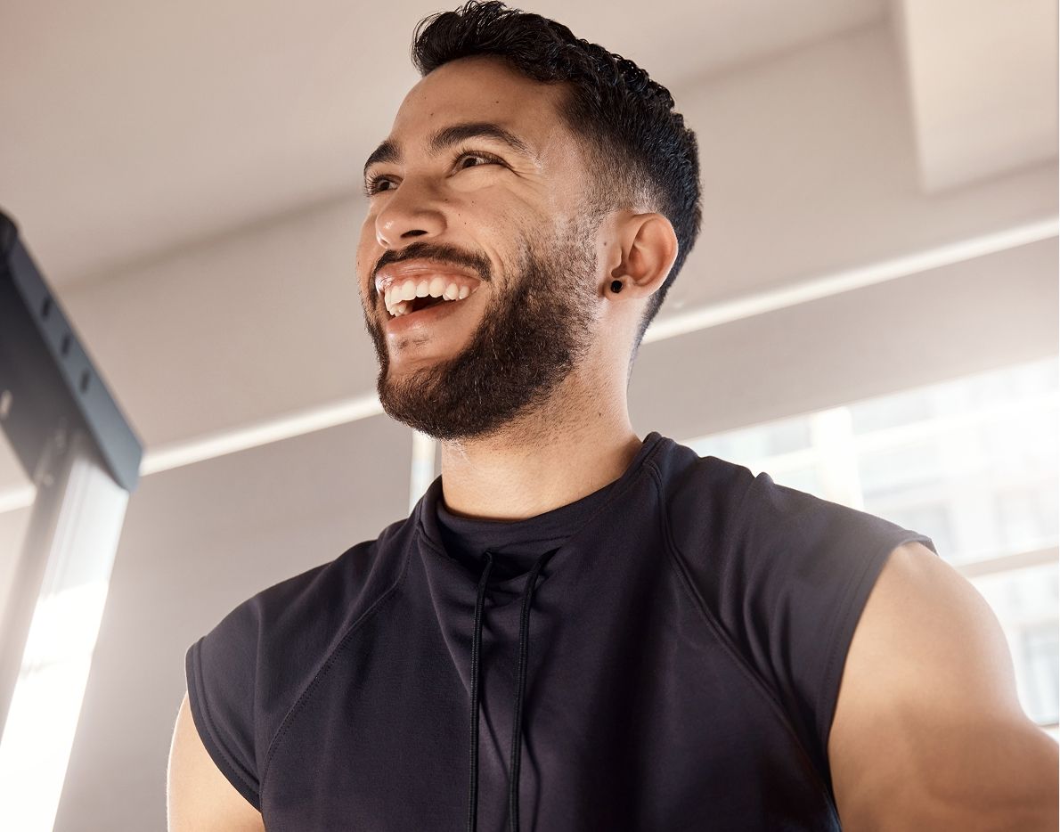 Smiling man in sports attire at gym.