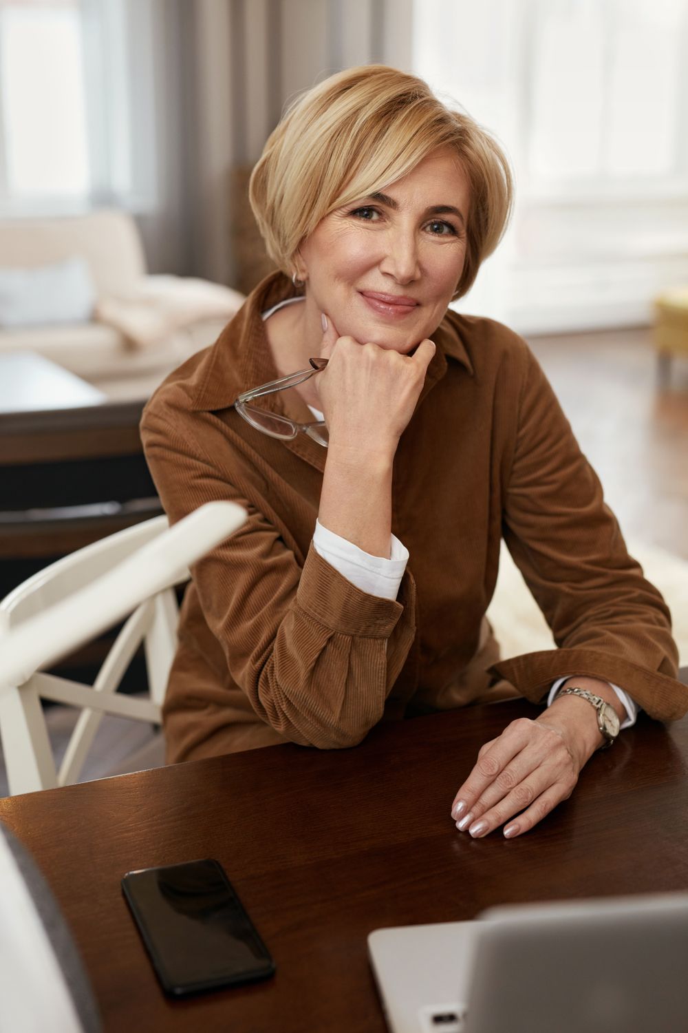 Smiling woman sitting at a desk thoughtfully.