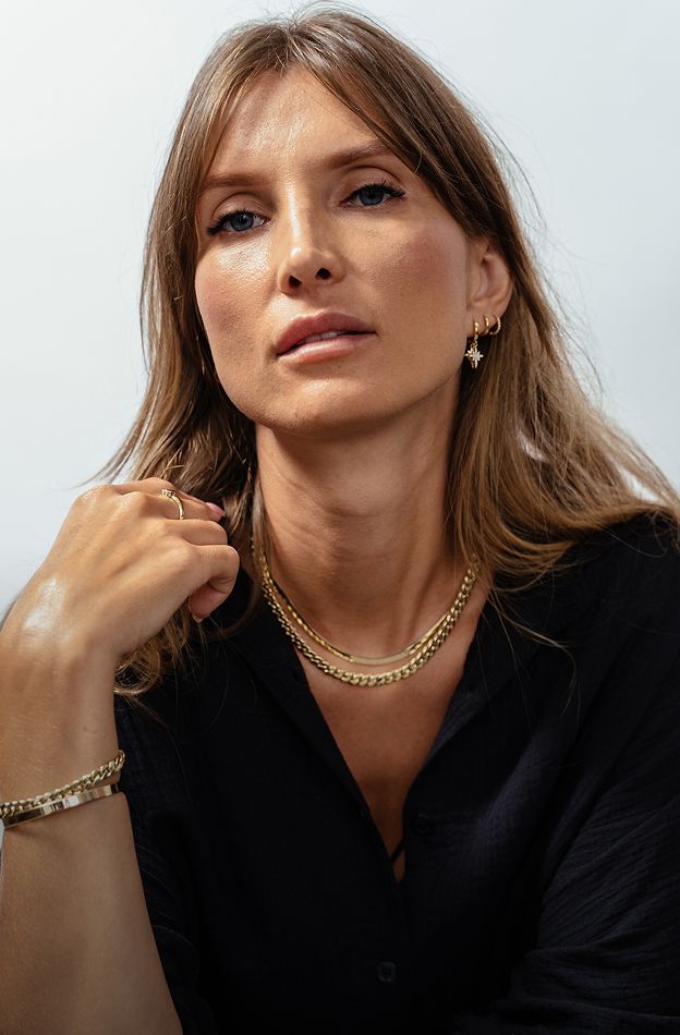 Woman wearing elegant gold jewelry and black shirt.